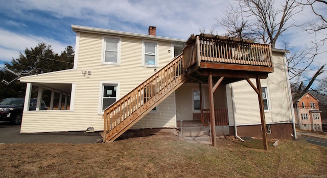 rear view of house featuring a chimney, stairs, and a yard