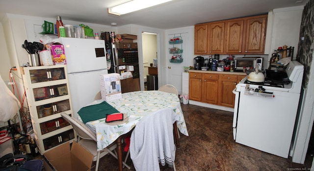 kitchen featuring concrete floors, light countertops, white range with gas stovetop, brown cabinets, and freestanding refrigerator