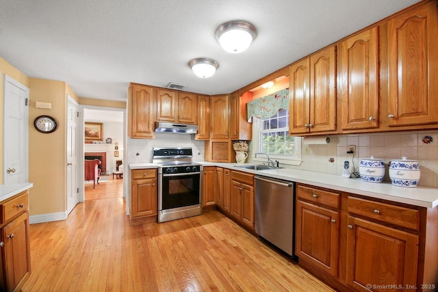 kitchen with visible vents, under cabinet range hood, dishwasher, electric stove, and a sink