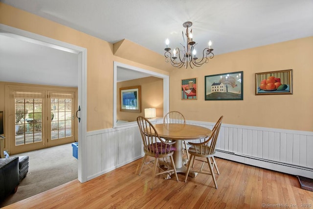 dining space with a wainscoted wall, a baseboard heating unit, an inviting chandelier, and hardwood / wood-style floors