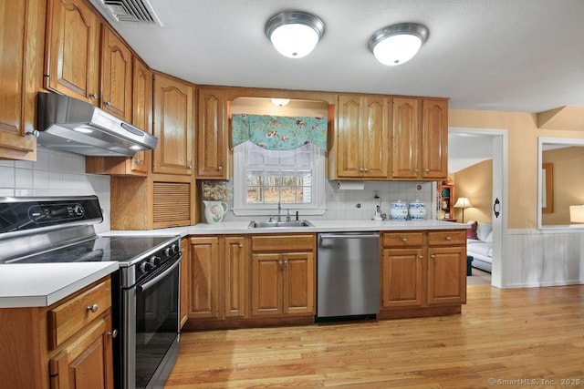 kitchen featuring visible vents, under cabinet range hood, a sink, appliances with stainless steel finishes, and light countertops