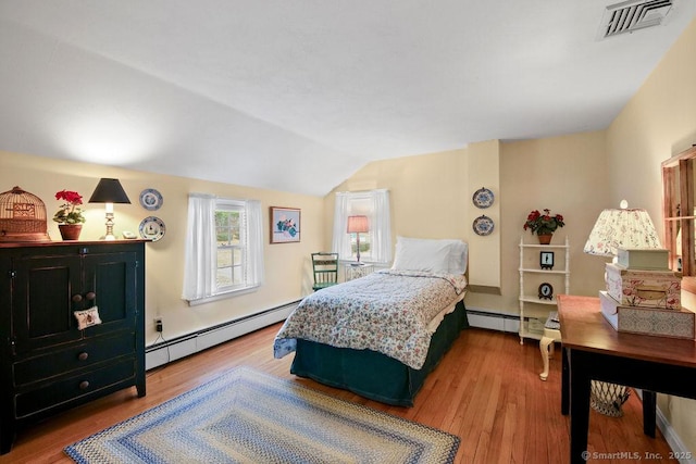 bedroom with vaulted ceiling, wood finished floors, visible vents, and a baseboard radiator