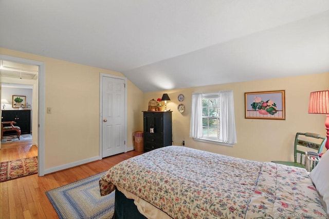 bedroom with baseboards, lofted ceiling, and wood finished floors