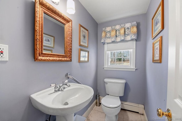 half bath with baseboards, a baseboard radiator, a sink, tile patterned flooring, and toilet