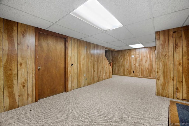 finished below grade area featuring wooden walls, carpet, and a drop ceiling