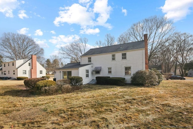 back of property featuring a lawn and a chimney