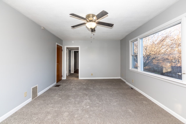 unfurnished room with visible vents, ceiling fan, carpet, and baseboards