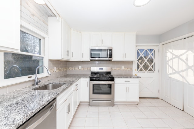 kitchen with a sink, stainless steel appliances, backsplash, and white cabinets