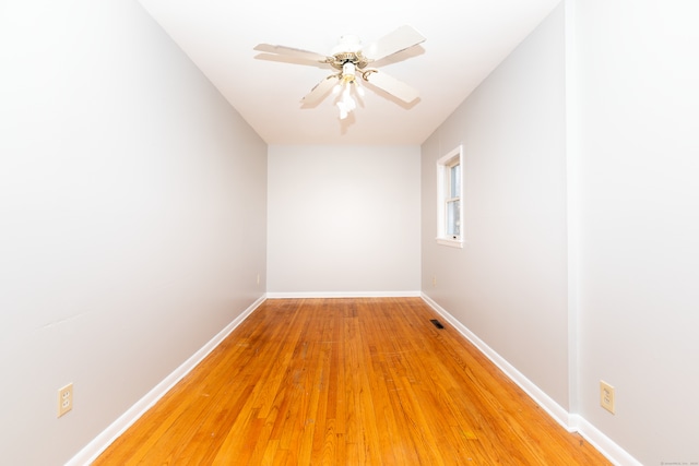 spare room featuring visible vents, baseboards, a ceiling fan, and light wood finished floors