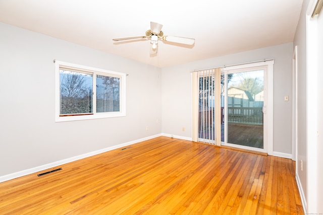 empty room with visible vents, a ceiling fan, baseboards, and hardwood / wood-style flooring