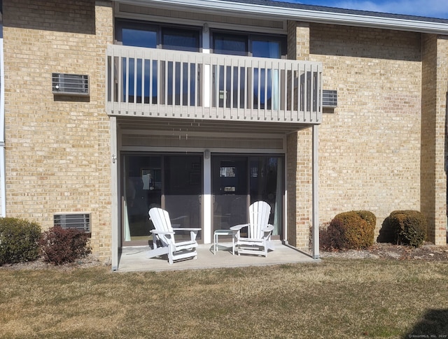 back of property with a balcony, a patio area, and brick siding