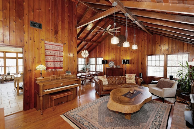 living area with wood finished floors, high vaulted ceiling, beam ceiling, ceiling fan, and wood walls