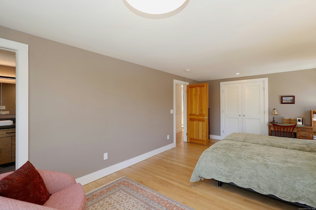 bedroom featuring baseboards, light wood-type flooring, and a closet