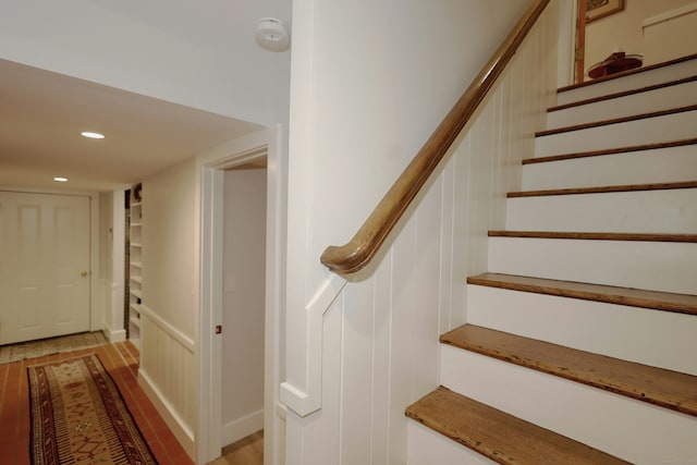 stairs featuring recessed lighting, wood finished floors, and a decorative wall