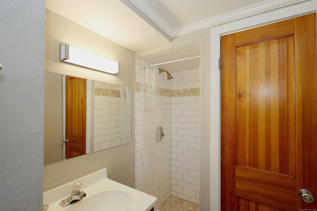 bathroom featuring a sink, tiled shower, and crown molding