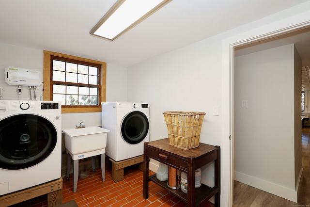 clothes washing area featuring a sink, laundry area, baseboards, and washing machine and clothes dryer