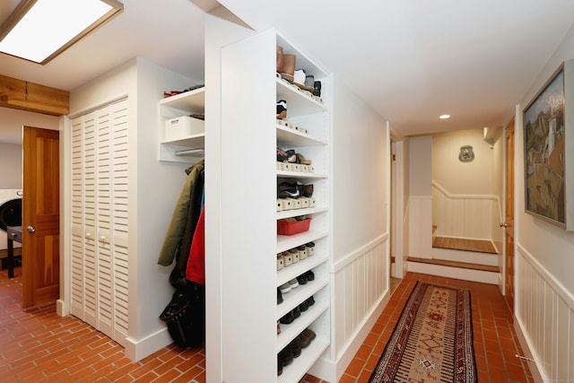 corridor featuring washer / dryer, brick floor, recessed lighting, and a wainscoted wall