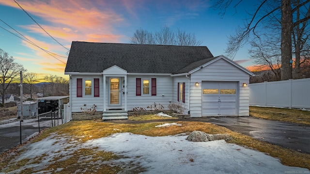 view of front of home with driveway, roof with shingles, an attached garage, and fence