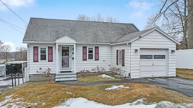 view of front facade with aphalt driveway, roof with shingles, a garage, and fence