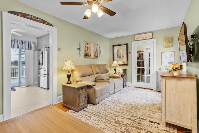 living area with visible vents, baseboards, light wood finished floors, and ceiling fan