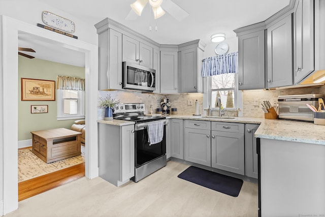 kitchen with a sink, stainless steel appliances, a ceiling fan, and gray cabinets