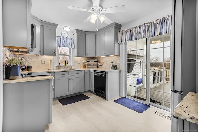 kitchen featuring backsplash, gray cabinetry, black dishwasher, and a sink