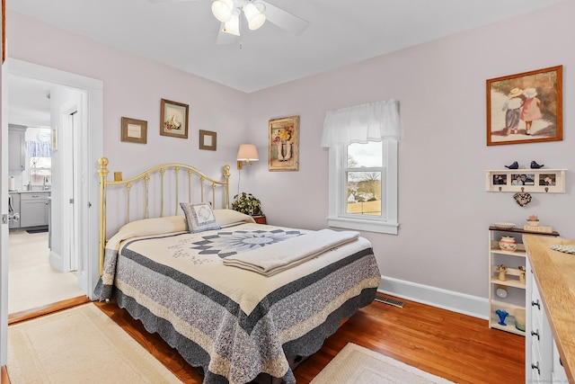 bedroom with multiple windows, wood finished floors, visible vents, and baseboards