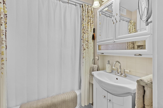 bathroom with visible vents, backsplash, vanity, and shower / tub combo