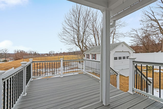 wooden terrace featuring an outbuilding, a garage, and fence