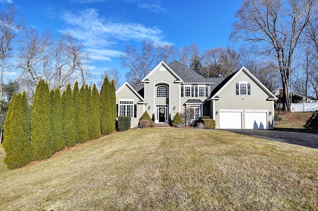 traditional-style home with a garage, a front yard, and driveway