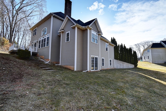 view of home's exterior with stairway, a yard, and a chimney