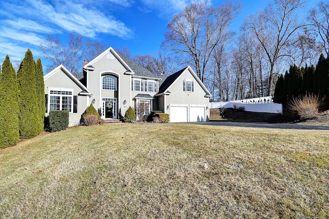 view of front of home with an attached garage, a chimney, driveway, and a front lawn