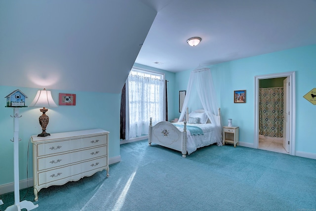 carpeted bedroom with baseboards, ensuite bath, and vaulted ceiling