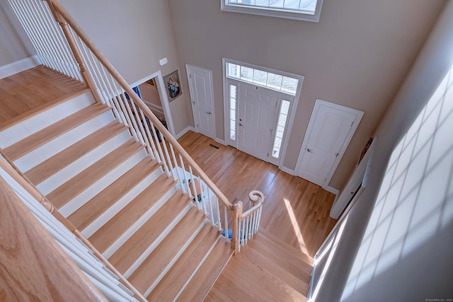 entrance foyer featuring a wealth of natural light, baseboards, a high ceiling, and wood finished floors