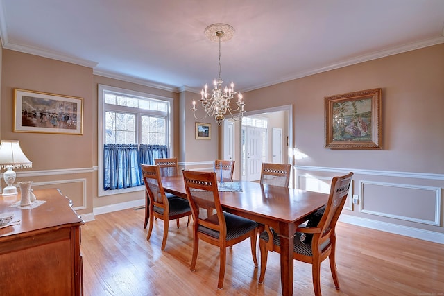 dining room featuring wainscoting, crown molding, and light wood-type flooring