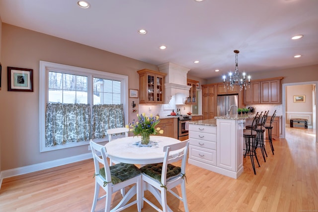 kitchen with tasteful backsplash, premium range hood, a breakfast bar, light wood-type flooring, and stainless steel appliances