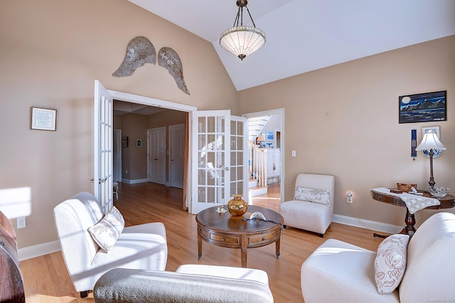 living room featuring high vaulted ceiling, french doors, light wood-type flooring, and baseboards