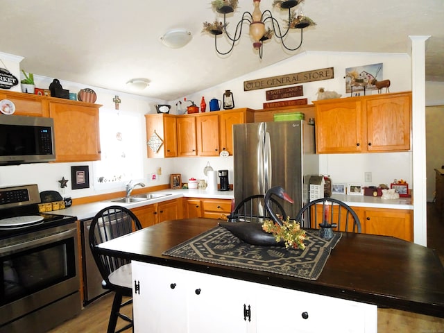 kitchen featuring lofted ceiling, a sink, appliances with stainless steel finishes, a notable chandelier, and light wood-type flooring