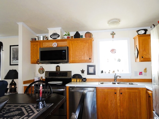 kitchen featuring ornamental molding, stainless steel appliances, light countertops, and a sink