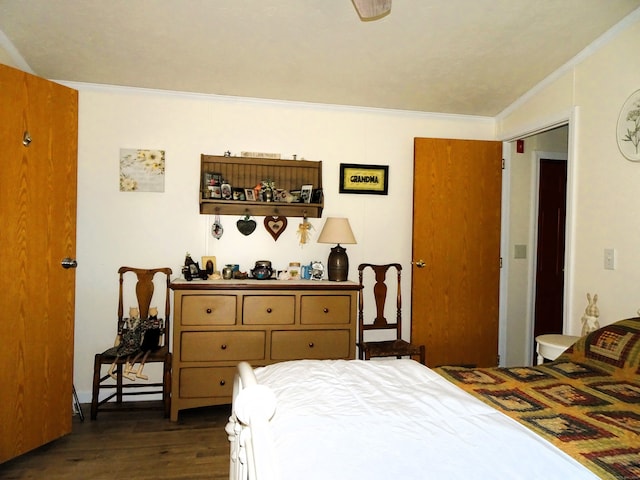 bedroom featuring ornamental molding and dark wood finished floors