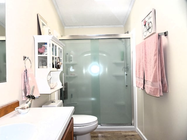 full bath featuring a stall shower, toilet, vanity, and ornamental molding