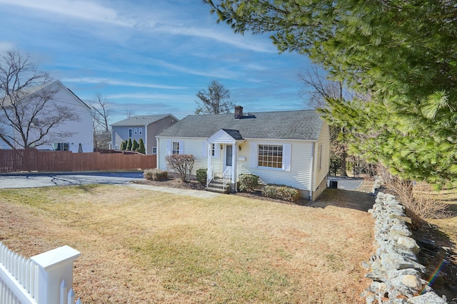 bungalow featuring a chimney, a front yard, and fence