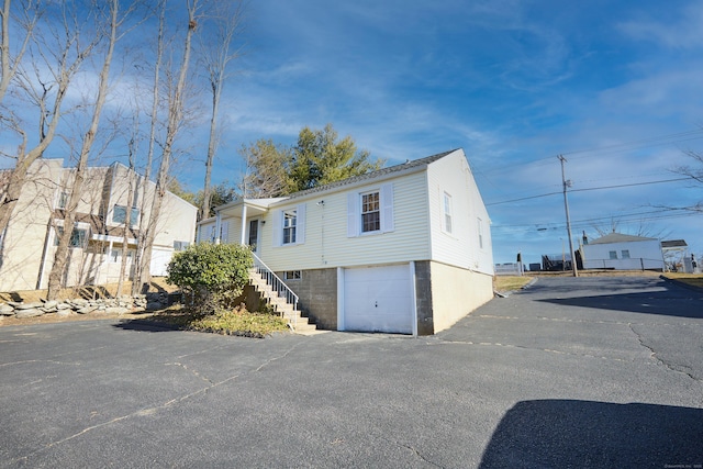 exterior space with stairs, an attached garage, and driveway