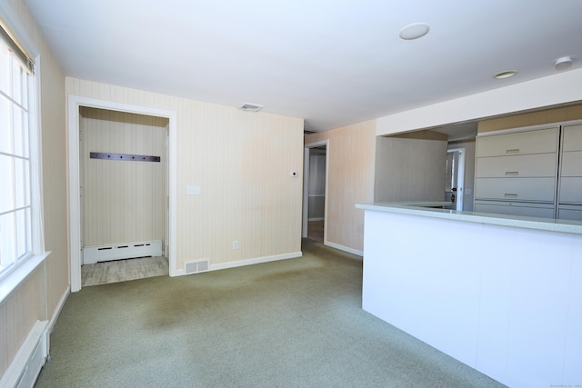 carpeted spare room with a baseboard radiator, baseboards, visible vents, and a healthy amount of sunlight