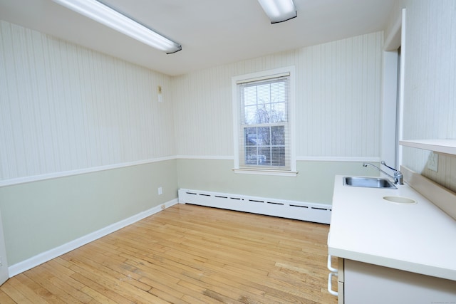 interior space with light wood finished floors, a sink, baseboards, and a baseboard radiator