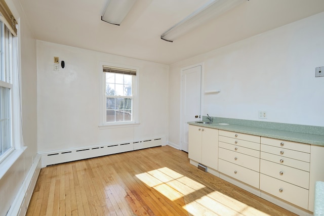 unfurnished room featuring light wood-style flooring and a baseboard heating unit