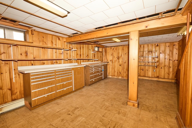 below grade area with baseboard heating, light floors, and wood walls