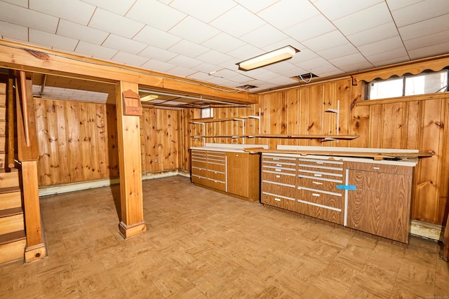 basement featuring wood walls, a baseboard heating unit, and light floors