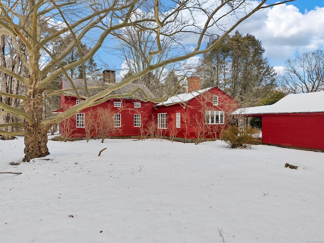 view of snow covered exterior with a chimney