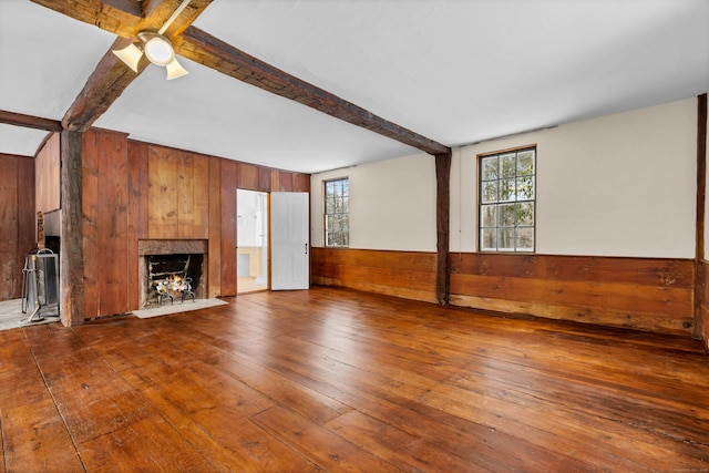 unfurnished living room featuring beamed ceiling and wood walls